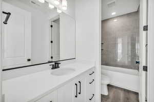 Full bathroom with tiled shower / bath, toilet, vanity, and hardwood / wood-style flooring