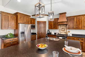 Kitchen with pendant lighting, custom exhaust hood, sink, and appliances with stainless steel finishes!