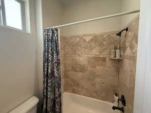 Bathroom featuring shower / bath combination with curtain and toilet