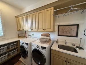 Laundry area featuring cabinets, sink, and washing machine and dryer