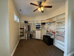 Spacious closet featuring dark carpet and ceiling fan