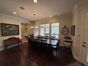 Dining space with crown molding, dark hardwood / wood-style flooring, and a chandelier