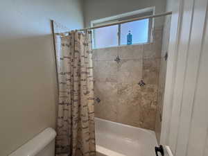 Bathroom featuring shower / bath combo and toilet