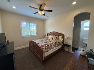 Bedroom with dark colored carpet, multiple windows, and ceiling fan