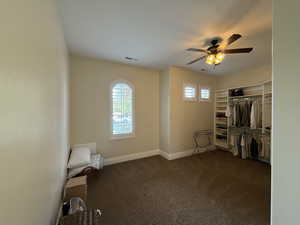 Interior space with dark colored carpet and ceiling fan