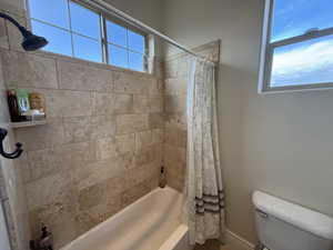 Bathroom with toilet and shower / tub combo with curtain