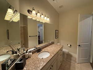 Bathroom with tiled shower, vanity, and toilet