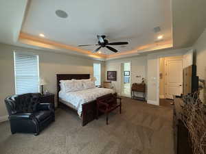 Bedroom with a raised ceiling, ceiling fan, and carpet floors