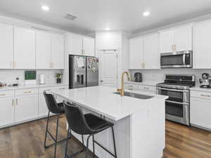 Kitchen with white cabinetry, sink, an island with sink, and appliances with stainless steel finishes