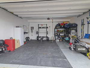 Garage featuring white fridge and a garage door opener