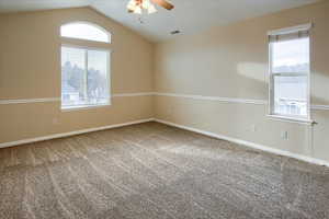 Carpeted spare room with ceiling fan and vaulted ceiling