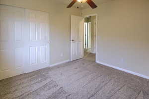 Unfurnished bedroom featuring ceiling fan, light colored carpet, and a closet