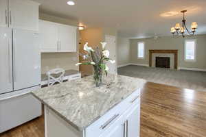 Kitchen featuring a tile fireplace, decorative light fixtures, white cabinets, a center island, and white fridge