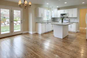 Kitchen with pendant lighting, a center island, white appliances, and light hardwood / wood-style flooring