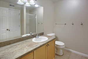 Bathroom with toilet, vanity, tile patterned floors, and an enclosed shower