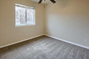 Carpeted empty room featuring ceiling fan