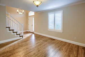 Entrance foyer featuring hardwood / wood-style floors, crown molding, and a chandelier