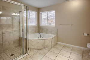 Bathroom with toilet, separate shower and tub, and tile patterned floors