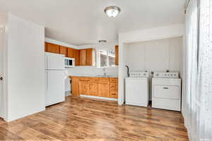 Clothes washing area with washer and dryer, wood-type flooring, and sink