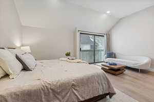 Bedroom with vaulted ceiling, access to outside, and light hardwood / wood-style flooring