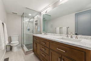 Bathroom featuring vanity, toilet, a shower with shower door, and wood-type flooring