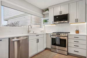 Kitchen featuring white cabinets, sink, stainless steel appliances, and tasteful backsplash