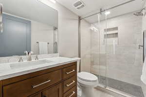 Bathroom featuring vanity, toilet, and a shower with shower door