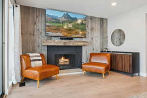 Sitting room featuring a fireplace, wooden walls, and light hardwood / wood-style flooring