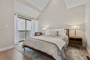 Bedroom featuring access to exterior, light hardwood / wood-style floors, and lofted ceiling