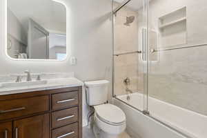 Full bathroom with vanity, toilet, and shower / bath combination with glass door