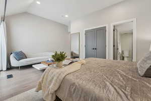 Bedroom with lofted ceiling, ensuite bathroom, and light hardwood / wood-style floors