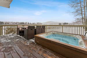 Snow covered deck featuring an outdoor hot tub and a mountain view