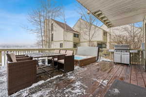 Snow covered deck with area for grilling and a covered hot tub