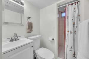 Bathroom with tile patterned floors, vanity, toilet, and a shower with shower curtain