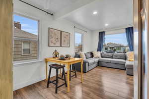 Living room with beamed ceiling, ceiling fan, light hardwood / wood-style floors, and a wealth of natural light