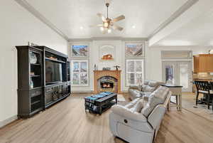 Living room with a textured ceiling, light hardwood / wood-style flooring, and ceiling fan