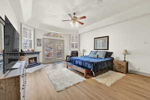 Main Bedroom with a tray ceiling, ceiling fan, light hardwood / wood-style floors, and a textured ceiling