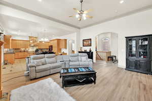 Living room with light hardwood / wood-style flooring, ceiling fan, crown molding, and sink