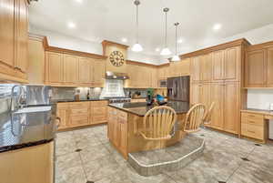 Kitchen featuring decorative light fixtures, a kitchen island, dark stone countertops, and stainless steel appliances