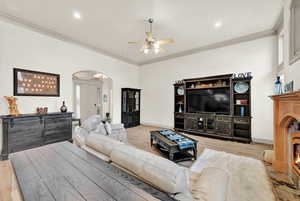 Living room featuring ceiling fan, light hardwood / wood-style floors, and crown molding