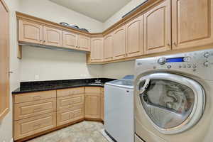 Main floor Laundry room with cabinets, sink, separate washer and dryer, a textured ceiling, and light tile patterned flooring