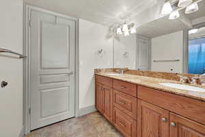 Third full Bathroom in basement  featuring vanity, a textured ceiling, an inviting chandelier, and tile patterned flooring