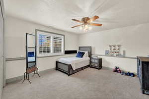 Fourth Bedroom in basement with ceiling fan, light carpet, and a textured ceiling