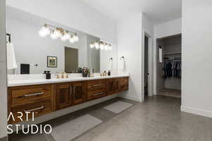 Bathroom with double vanity, baseboards, tile patterned flooring, a spacious closet, and a sink