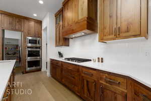 Kitchen featuring decorative backsplash, light hardwood / wood-style floors, and stainless steel appliances