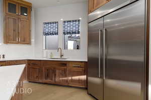 Kitchen featuring stainless steel built in refrigerator, light wood-type flooring, backsplash, and sink