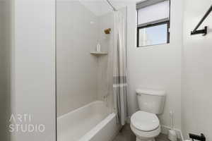 Bathroom featuring tile patterned floors, shower / bath combination with curtain, and toilet