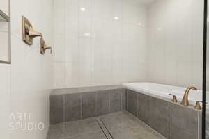 Bathroom with tile patterned floors, tile walls, and tiled tub