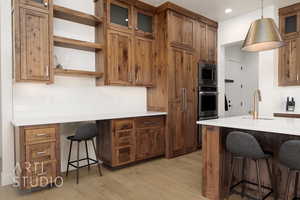 Kitchen featuring stainless steel microwave, a kitchen breakfast bar, sink, hanging light fixtures, and light wood-type flooring