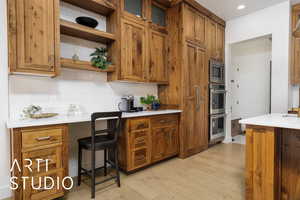 Kitchen with brown cabinets, stainless steel appliances, light countertops, and open shelves